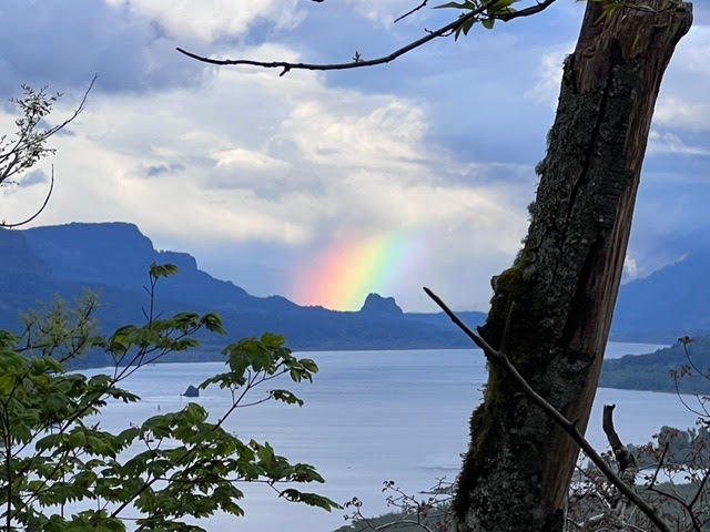 A bay with a rainbow over the rock formations in the background 